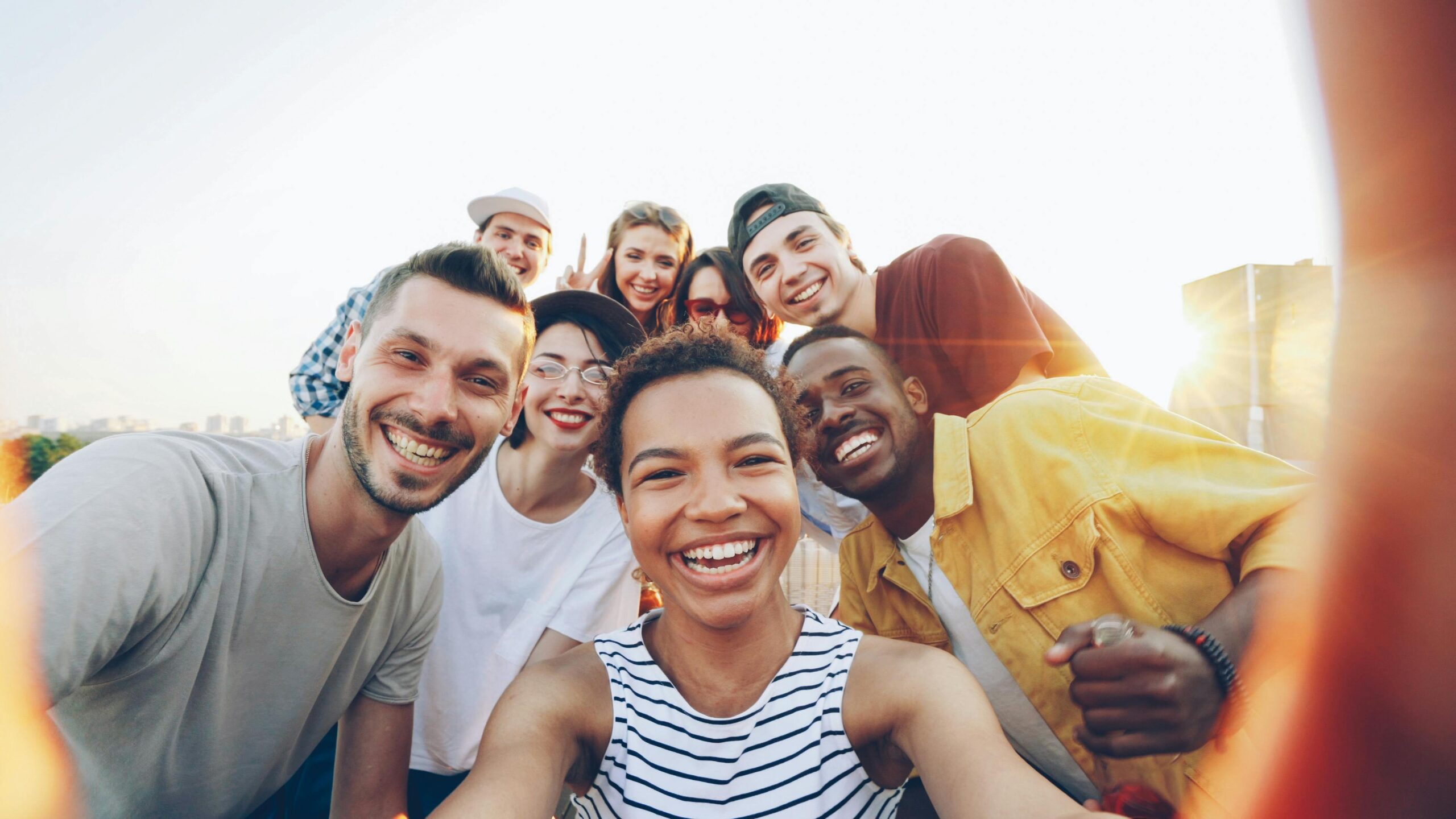 Home A diverse group of friends taking a joyful selfie outdoors during sunset.